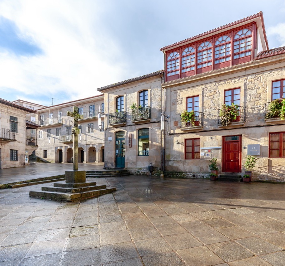 Spanien - Historischer Platz Praza da Lena in Pontevedra in Galicien. Gebäude mit farbiger Fassade, Holzfenstern, Balkonen und einem Steinkreuz in der Mitte.